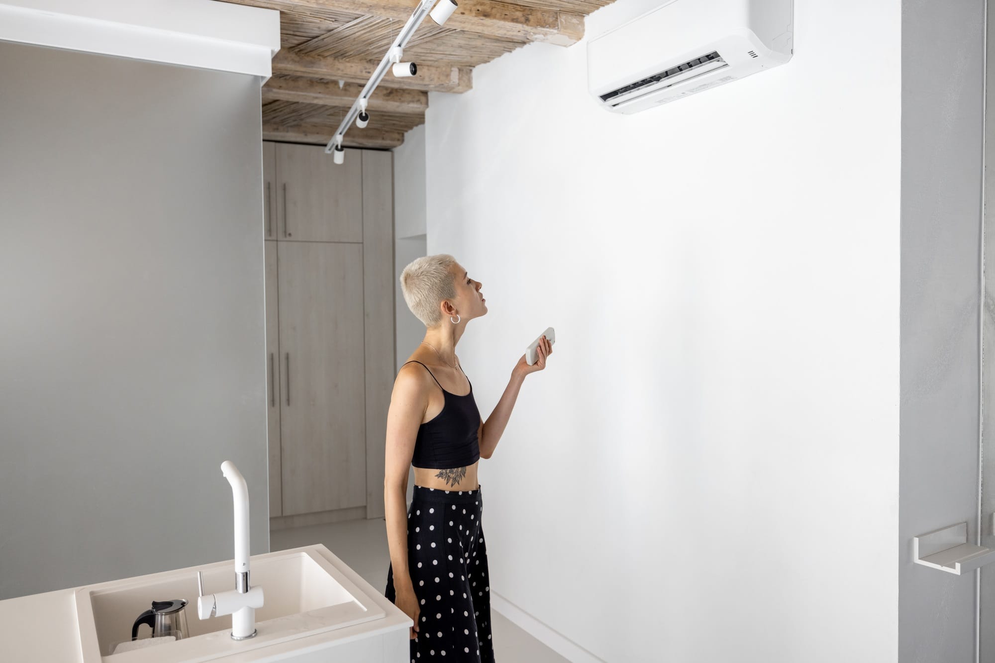 Woman sets the temperature on the air conditioner at home